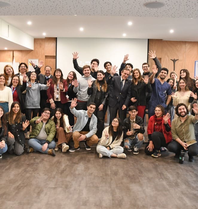 Grupo de líderes estudiantiles de la UC comparte con el rector Ignacio Sánchez mientras saludan a la cámara.