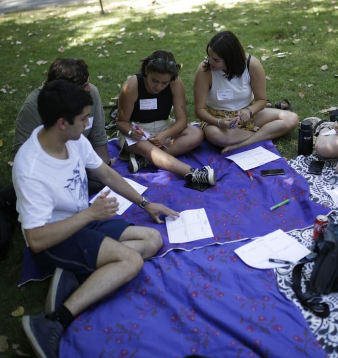 Grupo de estudiantes comparten sentados al aire libre al interior del campus San Joaquín.