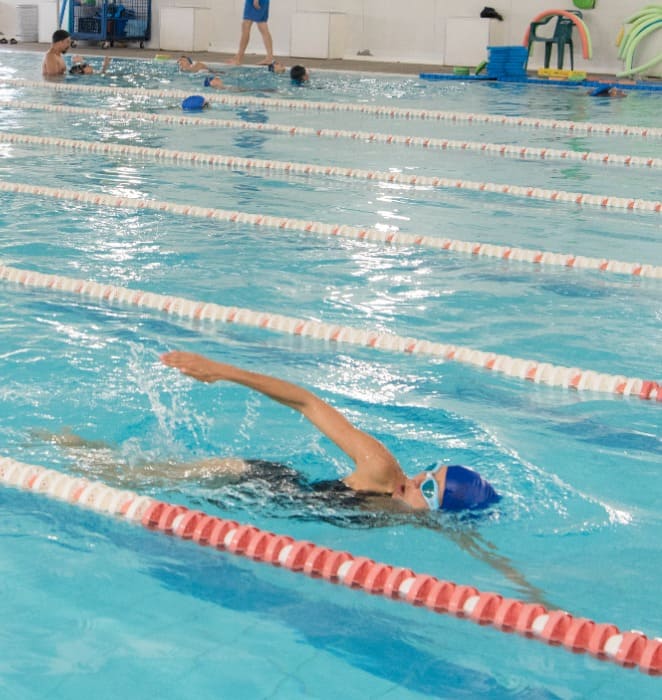 Persona realiza nado libre al interior de piscina ubicada al interior del gimansio de Deportes del campus San Joaquín.