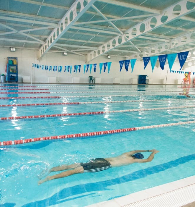 Persona practica natación al interior de piscina del gimansio del área deportes del campus San Joaquín.