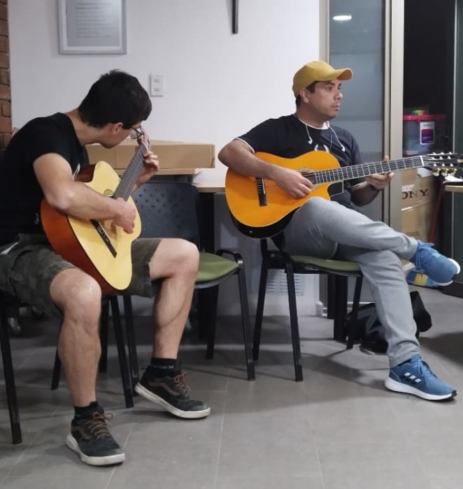 Dos estudiantes tocan la guitarra como parte de su entrenamiento en taller impartido en la PUC.