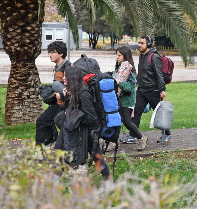 Grupo de estudiantes cargan mochilas durante los trabajos voluntarios patrocinados por la universidad.