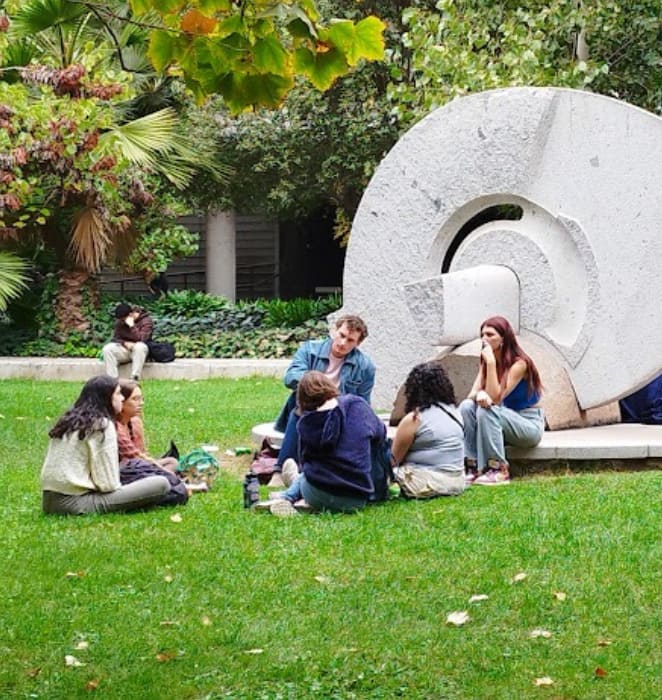 Grupo de 6 estudiantes, conversando relajadamente en patio de campus San Joaquín