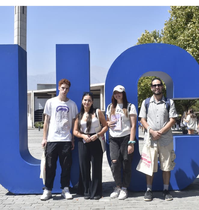 Grupo de cuatro estudiantes posando frente a las letras UC gigantes, en campus San Joaquín