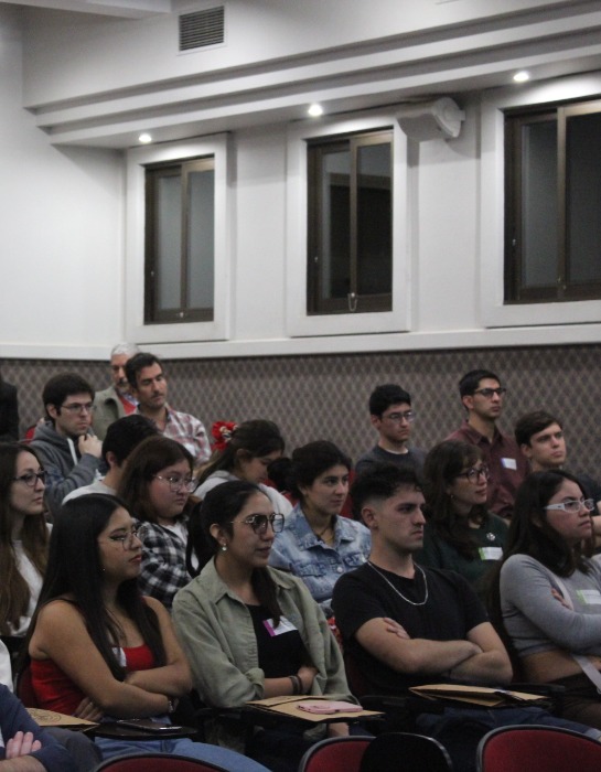 Grupo de estudiantes y comunidad académica PUC participa de ceremonia al interior de auditorio en el campus San Joaquín.