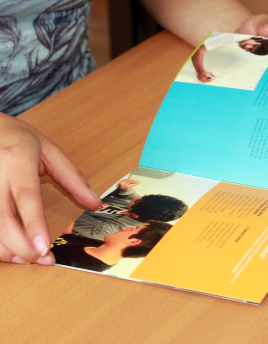 Imagen muestra manos de estudiante de la UC revisando folleto explicativo.