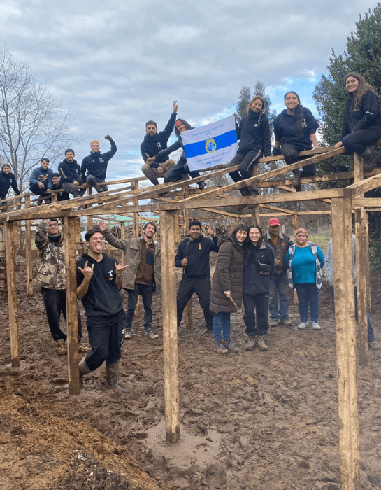 Estudiantes UC junto a una estructura para la construcción de una casa