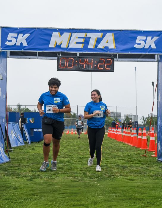 Fotografía de dos asistentes cruzando la meta de 5k del Running UC 2024.