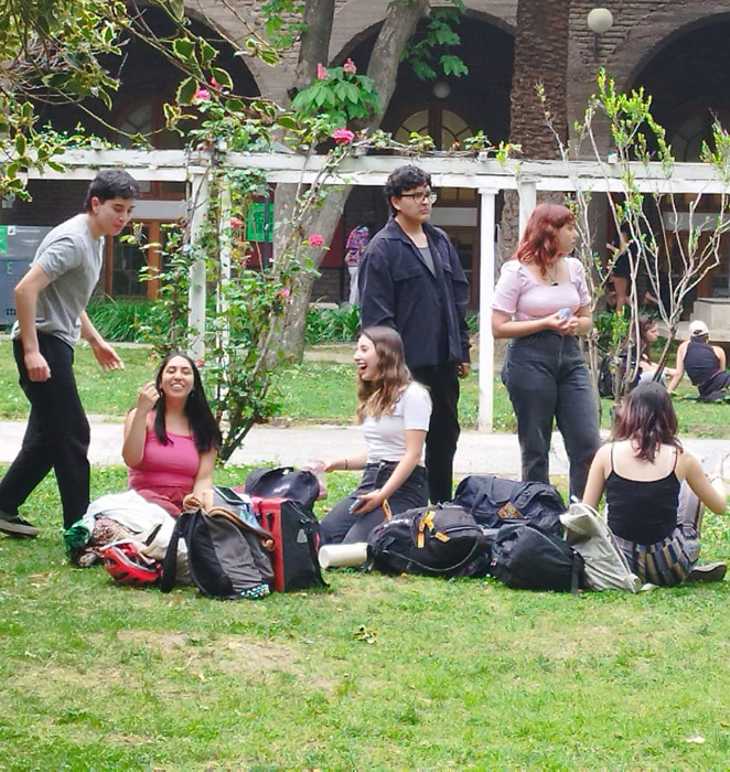 varios estudiantes conversando y revisando cosas en un pc, en campus oriente