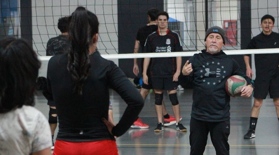 Profesor de vóleibol entrega instrucciones a sus estudiantes, en el contexto del taller del programa Reactívate UC Invierno 2025