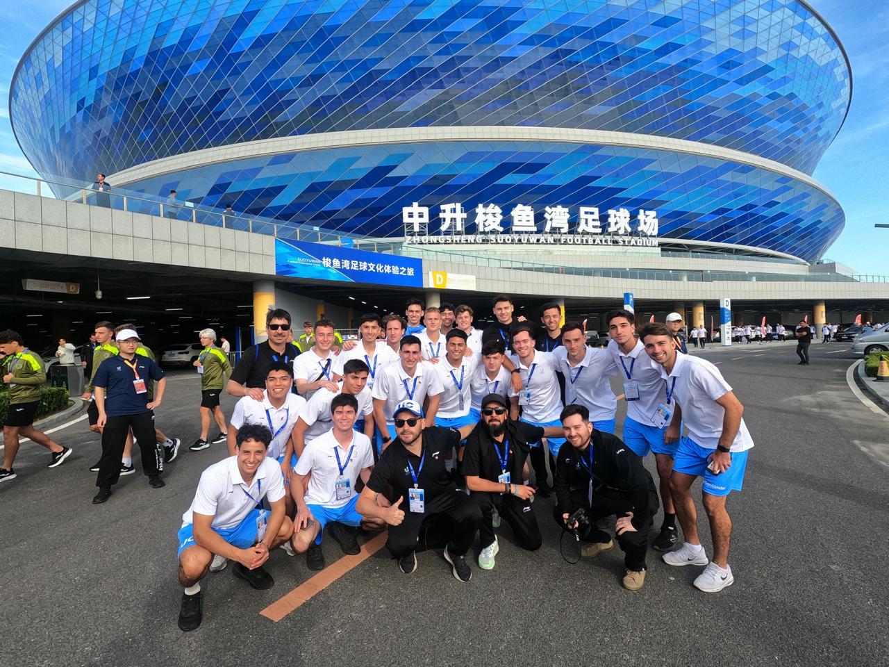Selección de Fútbol UC posando frente a un estadio en China, donde se desarrolló la Copa Mundial Universitaria de Fútbol 2025
